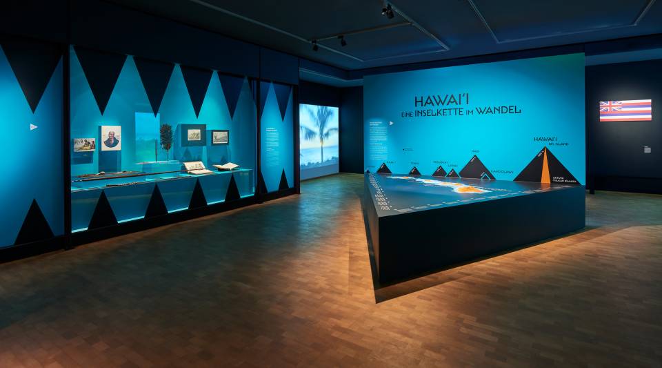 Ausstellungsansicht Hawaii. In einem türkis eingefärbten Raum wird die Inselkette vorgestellt