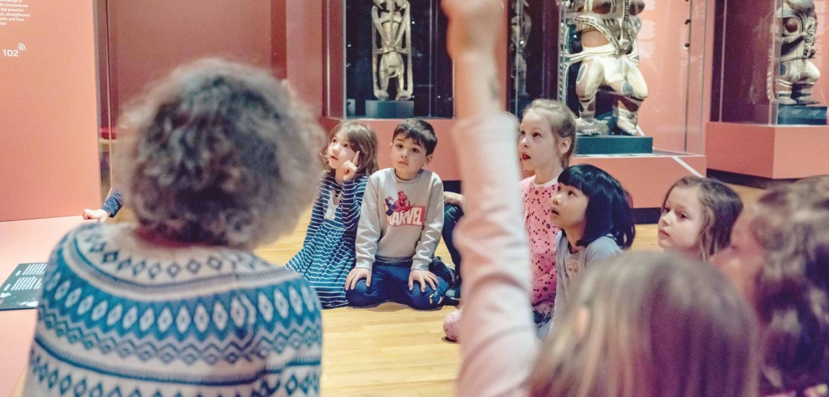 Kinder, auf dem Boden sitzend, während einer Führung in der Ausstellung "Ozeanien - Kontinent der Inseln"