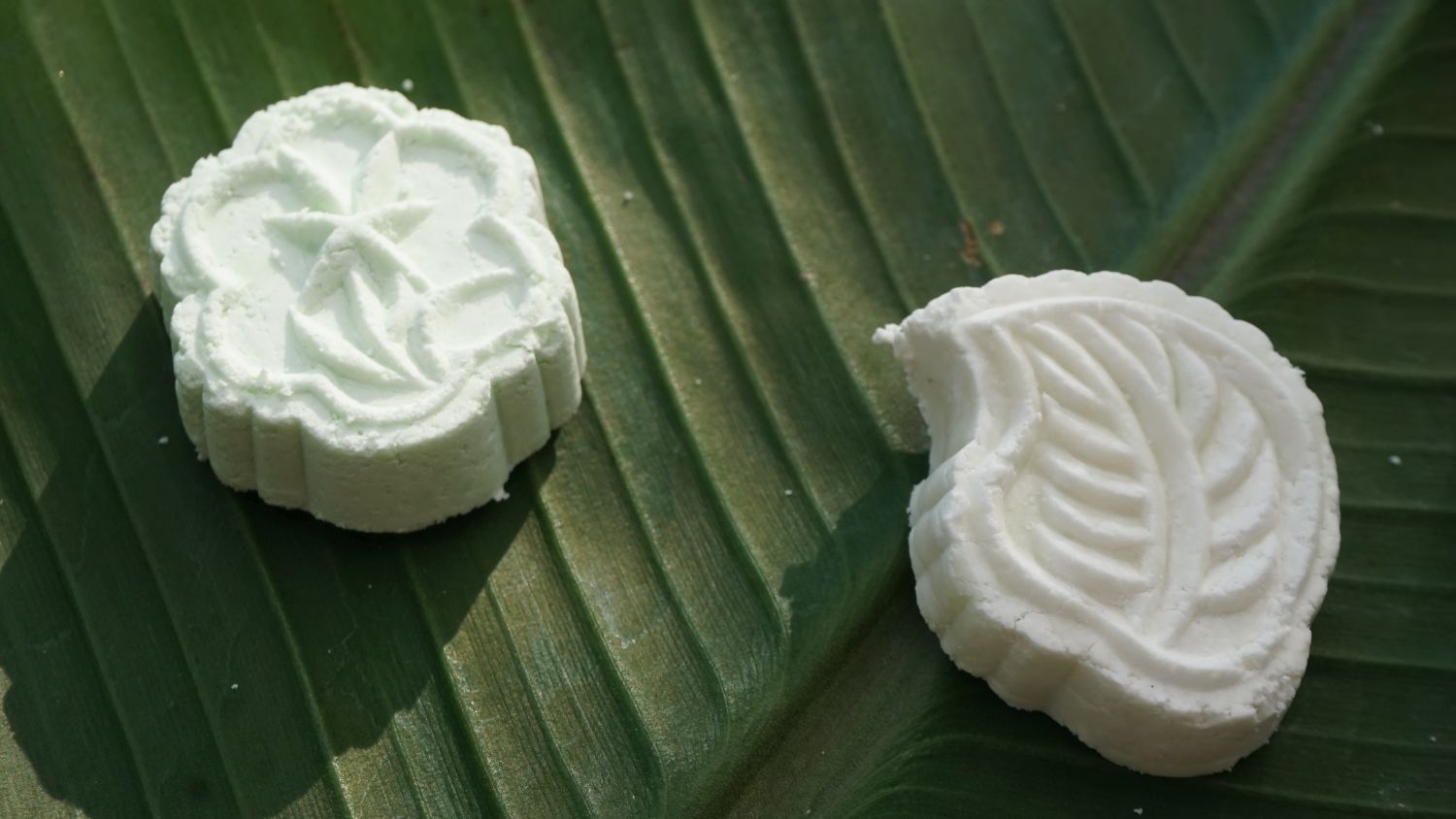 2 weiße Cookies aus Tapioka-Mehl in Blattformen auf einem grünen Blatt drapiert