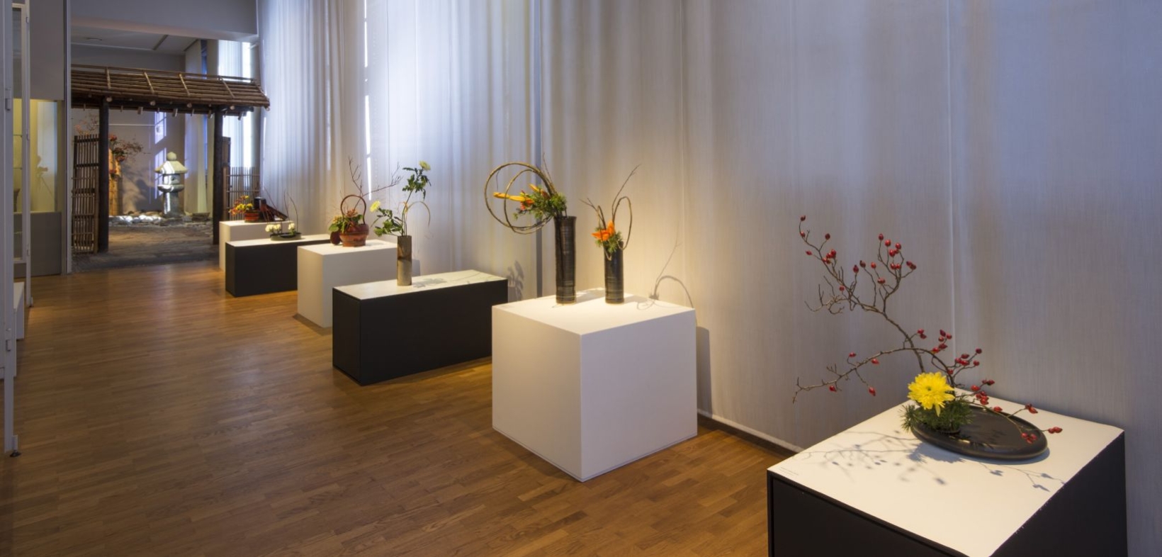 Verschiedene Ikebana-Gestecke auf Sockeln in der Ostasien-Ausstellung