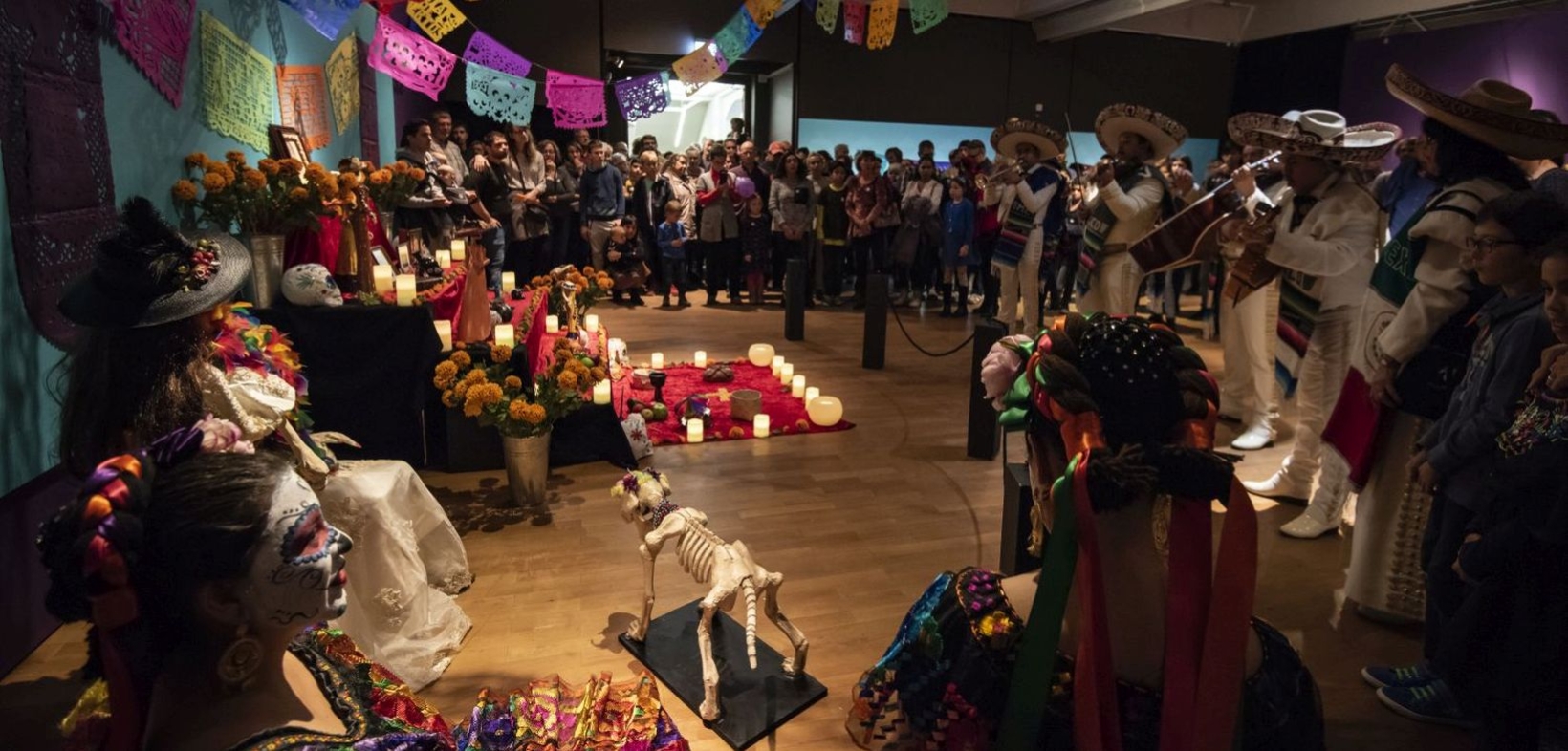 Mariachi-Kapelle spielt in abgedunkeltem Raum vor der Ofrenda, einem mexikanischen Gabentisch zum Totengedenken