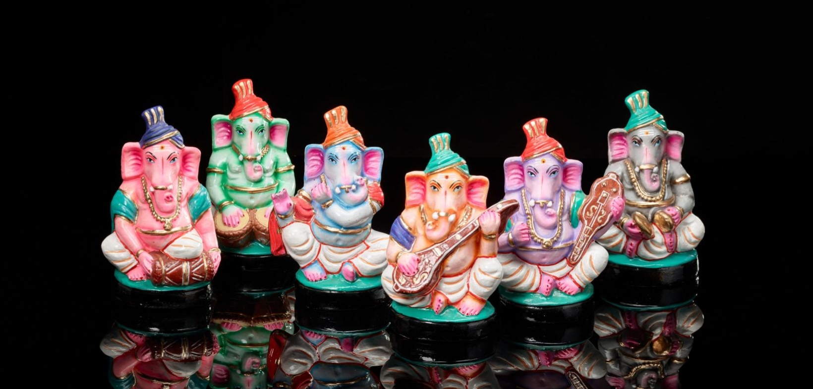 Musik spielende Ganeshas: eine sechsköpfige Band mit Instrumenten, bestehend aus bunten Plastikfiguren, die den elefantenköpfigen Gott Ganesha darstellen