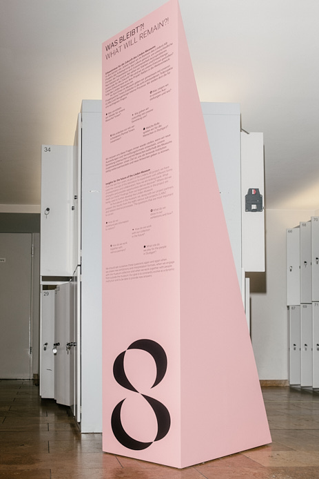 Ein rosafarbener dreieckiger Aufsteller mit der Ziffer 8 steht in der Garderobe des Museums